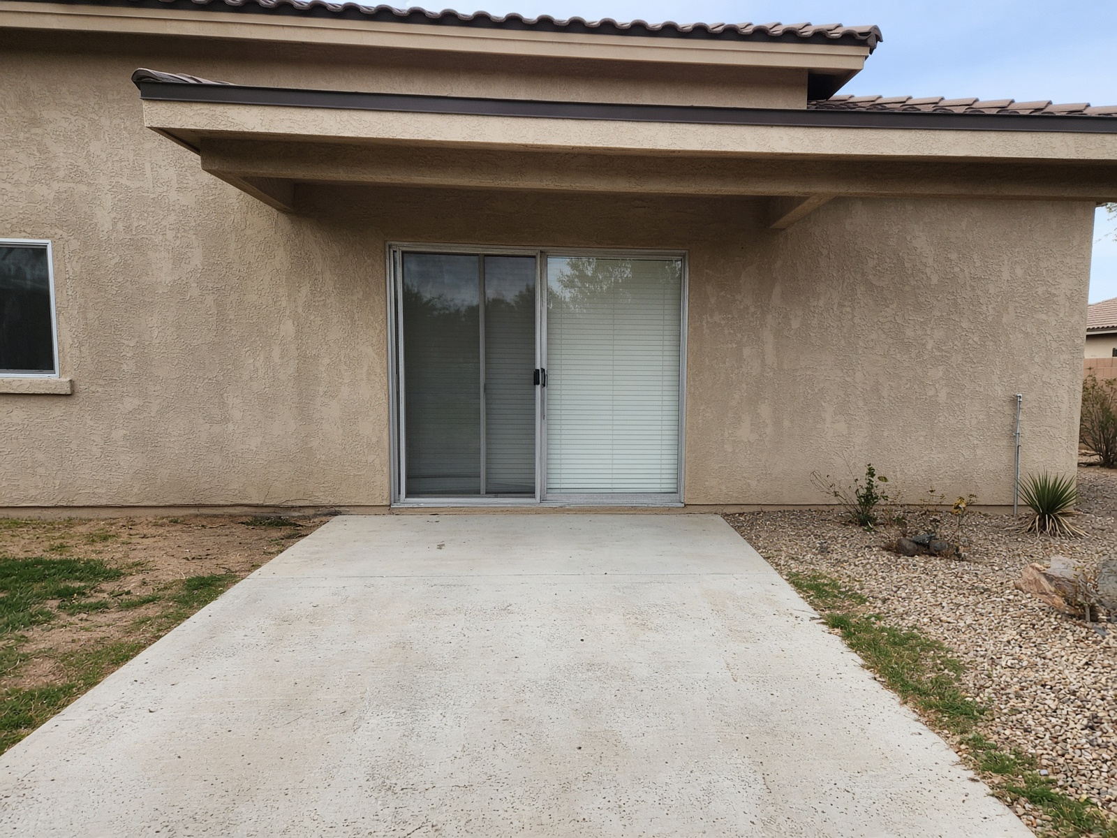 Rear of an Arizona house with an aluminum sliding door and a concrete patio